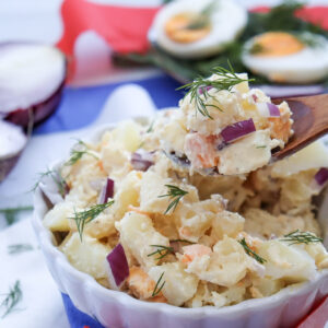 Potato salad being served with a large, wooden spoon.