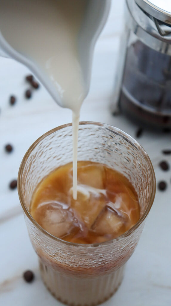 Pouring milk into caramel iced coffee.